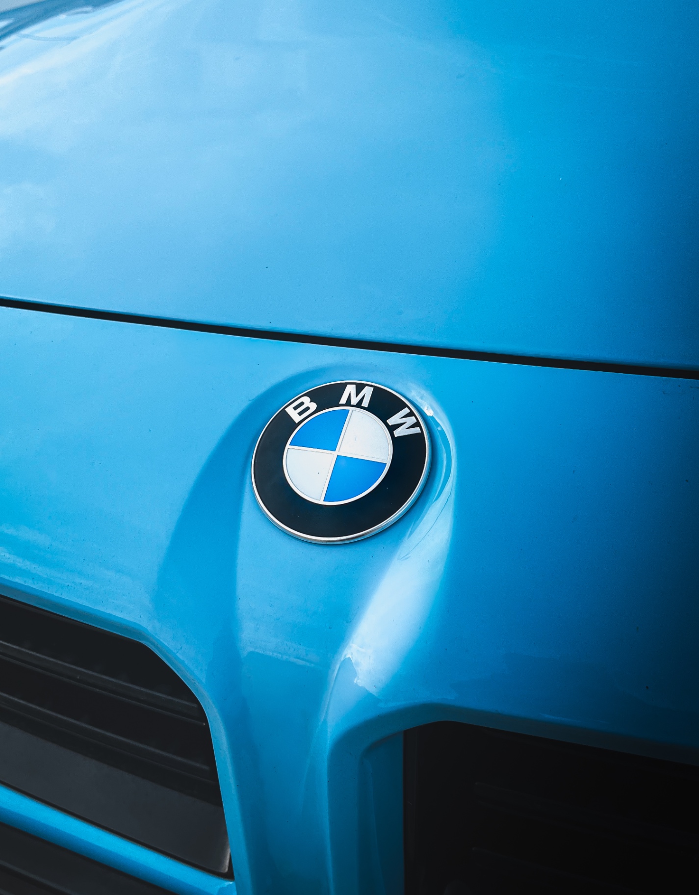 Emblema BMW azul e branco em capô azul vibrante de um BMW