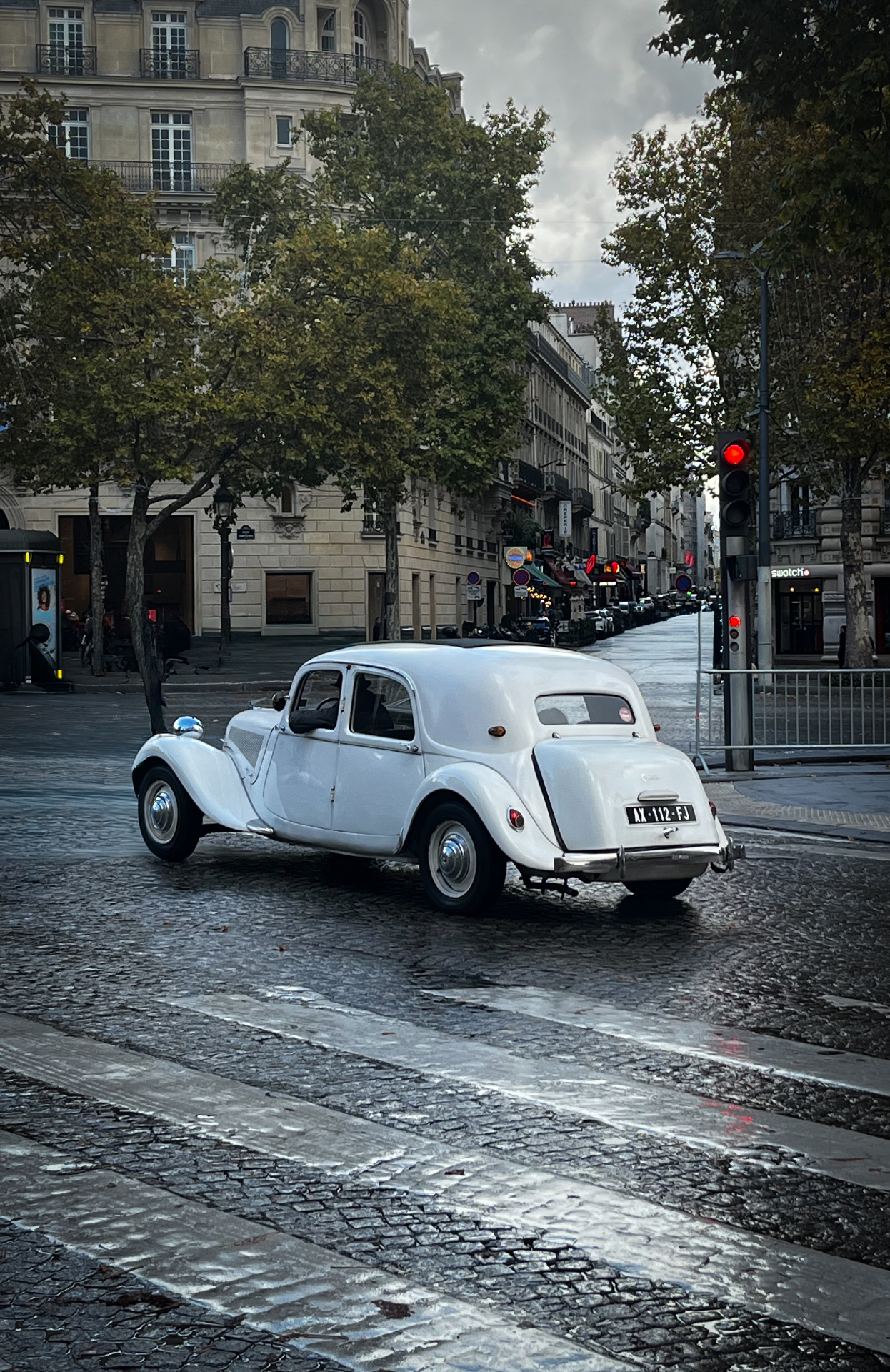 Citroën Traction Avant branco em rua de paralelepípedo molhada em Paris