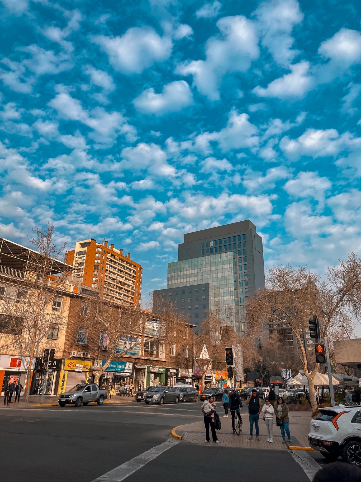 Céu cheio de nuvens fragmentadas sobre prédios e movimento de rua