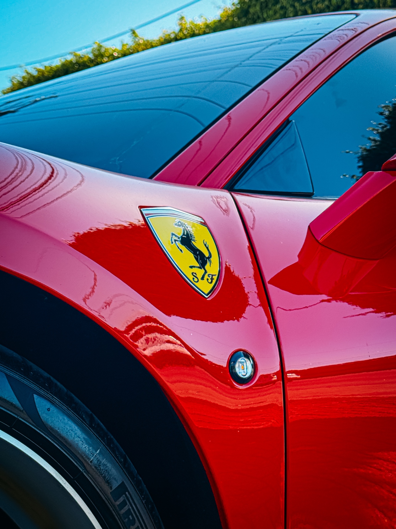 Escudo Scuderia Ferrari amarelo na para-lama de uma Ferrari vermelha sob luz dourada