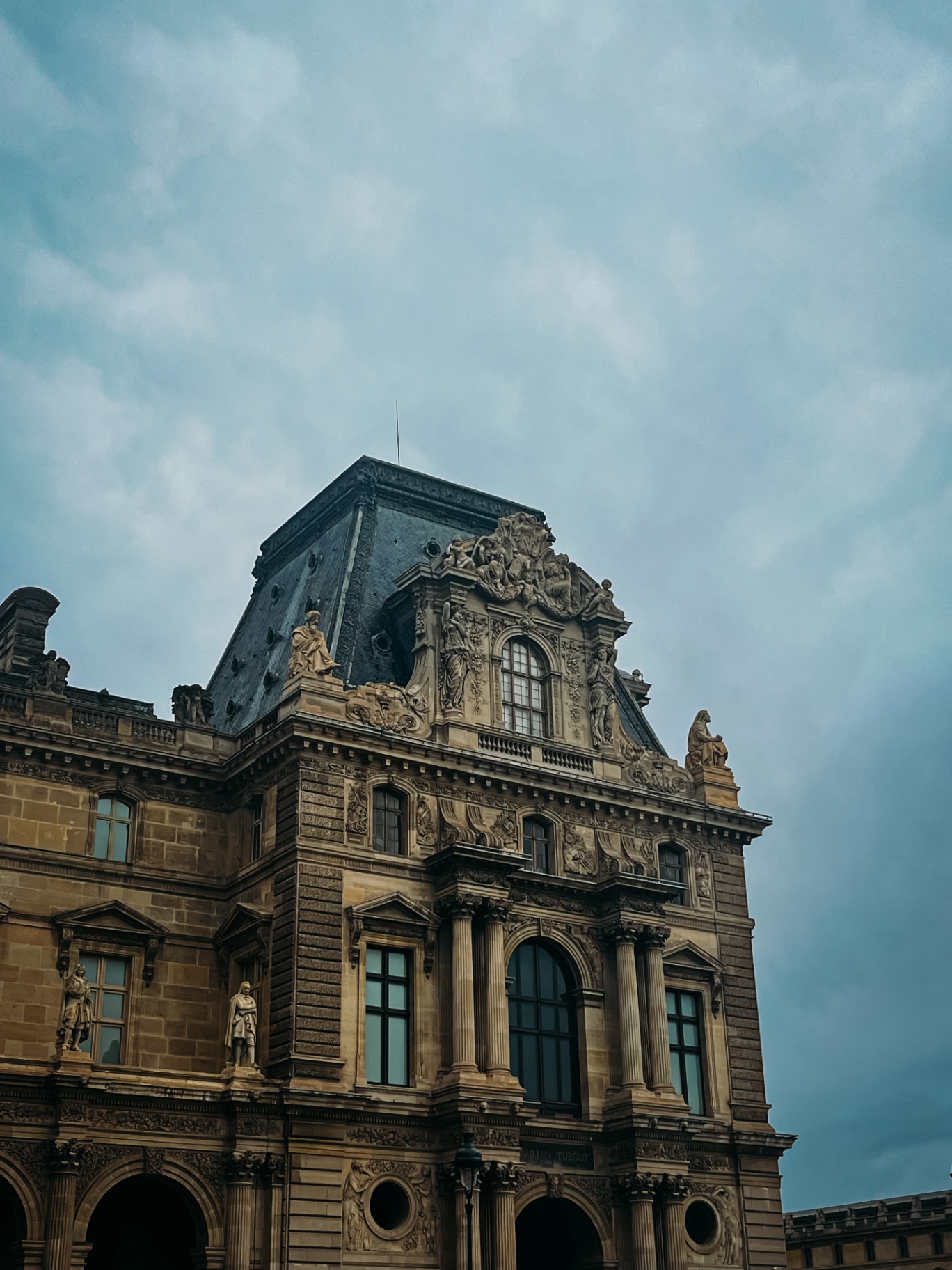 Fachada do Museu do Louvre em Paris sob céu nublado