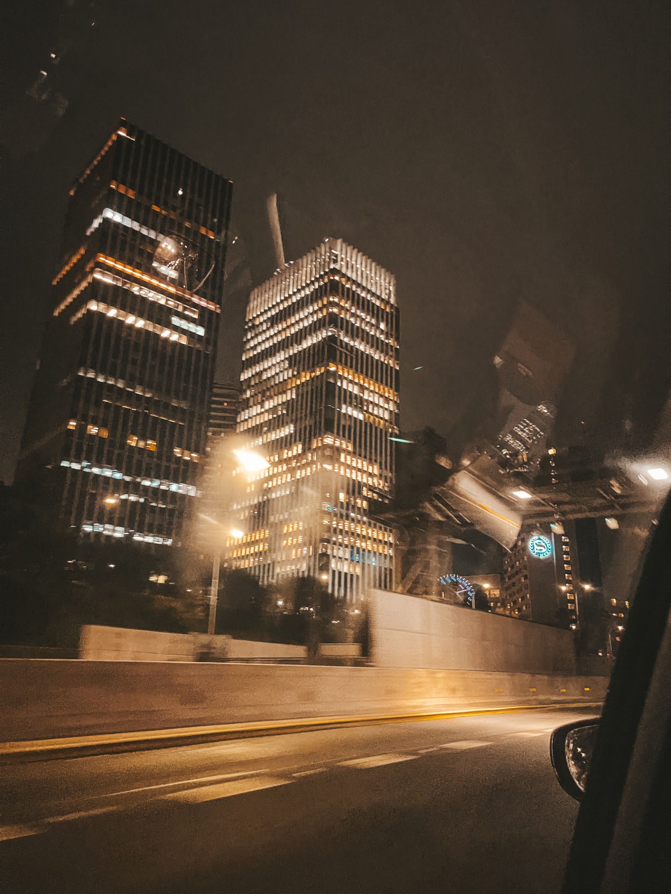 Arranha-céus iluminados à noite vistos da janela de um carro em movimento
